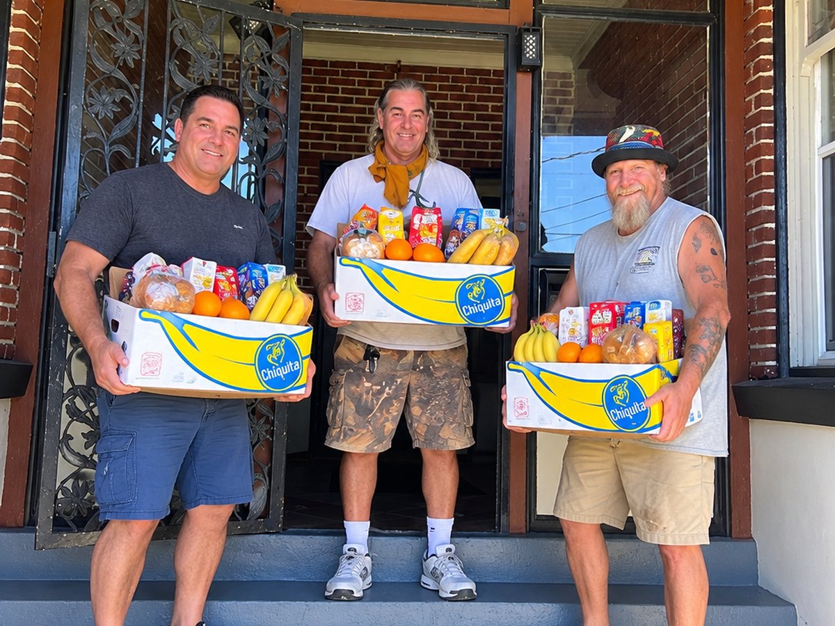 Men at Victory House holding boxes of groceries